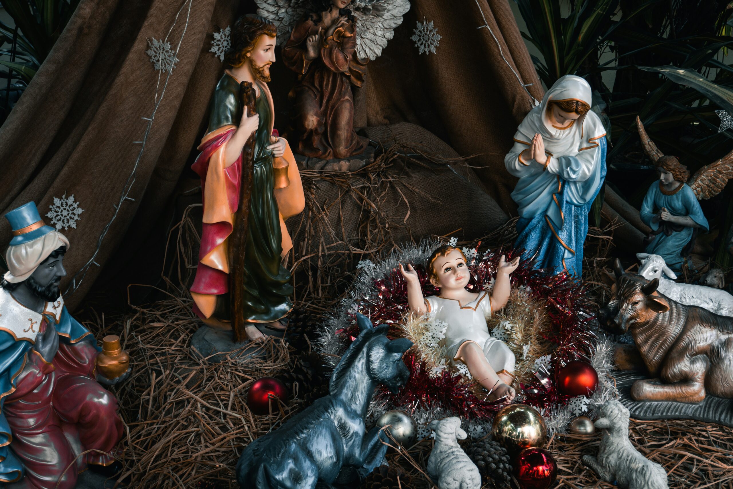 nativity scene for christmas with mary, joseph, and baby jesus depicted in a a barn with hay